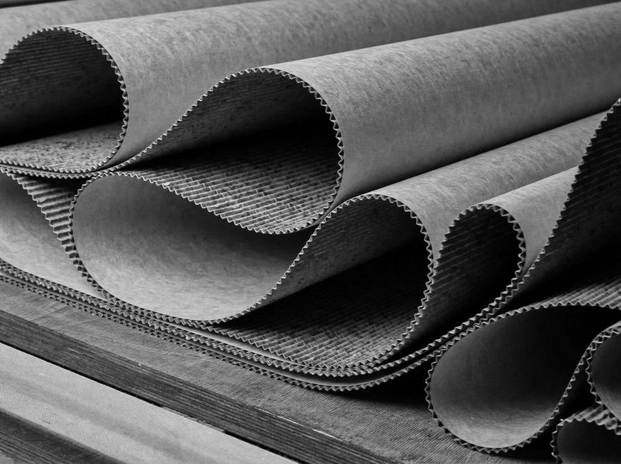 Rolls of corrugated medium and liner curling open on a timber pallet